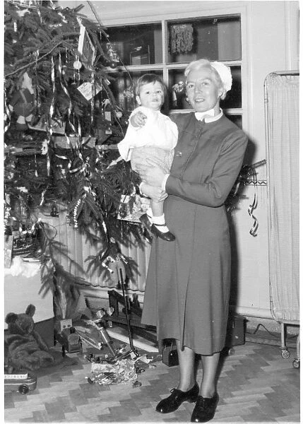 Nurse holding child next to Christmas tree