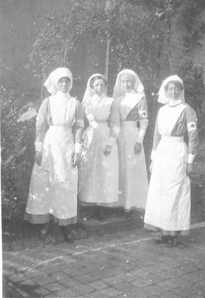 Four nurses in uniform, with red cross armbands