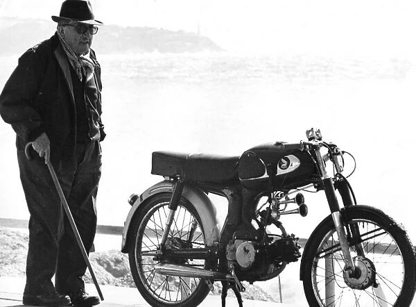 Old man standing next to a motorcycle near a beach