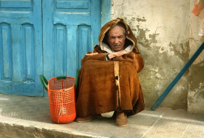 Framed Print : Old man wearing a djelleba sits on pavement, Tunisia Framed Print : Old man wearing a djelleba sits on pavement, Tunisia