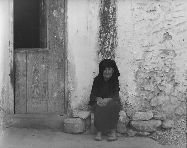 Old woman in black, sitting outside her home