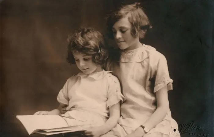 Framed Print : Older girl helps her younger sister read a book Framed Print : Older girl helps her younger sister read a book