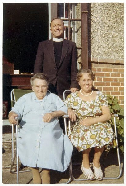 Two older women pose for a photograph with the local vicar