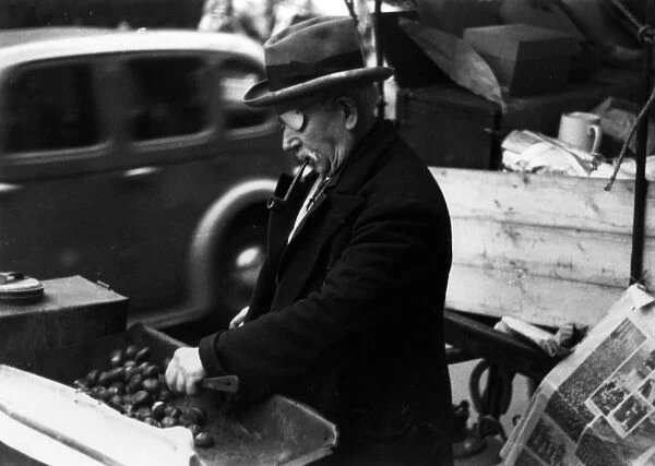 One-eyed man roasting chestnuts at market