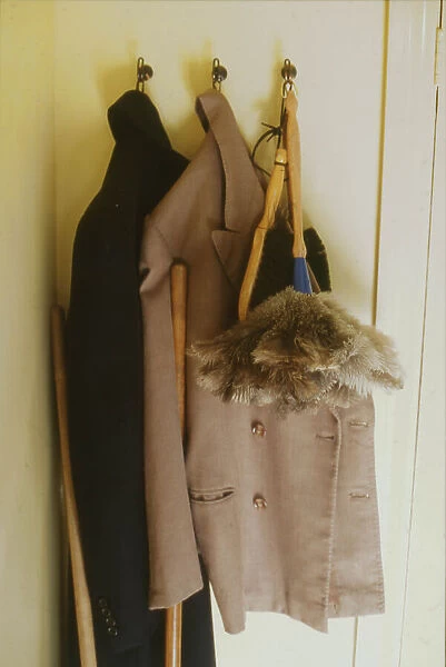 Two overcoats and a feather duster, hanging from three