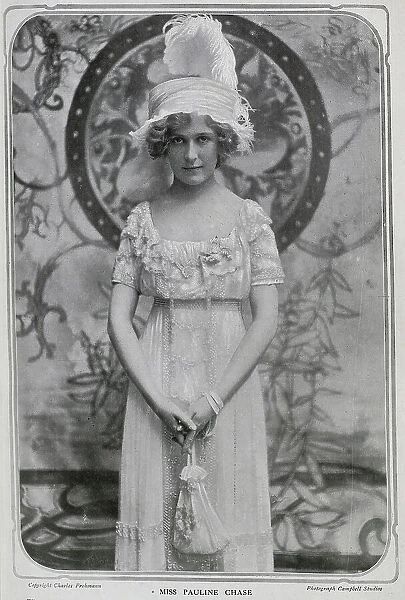Pauline Chase (1885-1962), American actress, studio portrait in gown and feathered hat. Captioned, Pan Re-Petered'. Chase had recently returned to London from New York, to play Peter Pan at the Duke of York's theatre