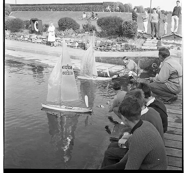 People with model sailing boats on a pond
