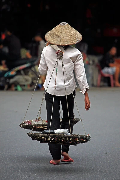 Person carrying traditional baskets in Hanoi, Vietnam