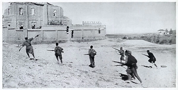 Photograph showing a Nationalist infantry unit, led by their officer (on left, with pistol), running across open ground towards a ruined house during the Spanish Civil War, 1936. This photograph was probably taken on the frontline south of Madrid