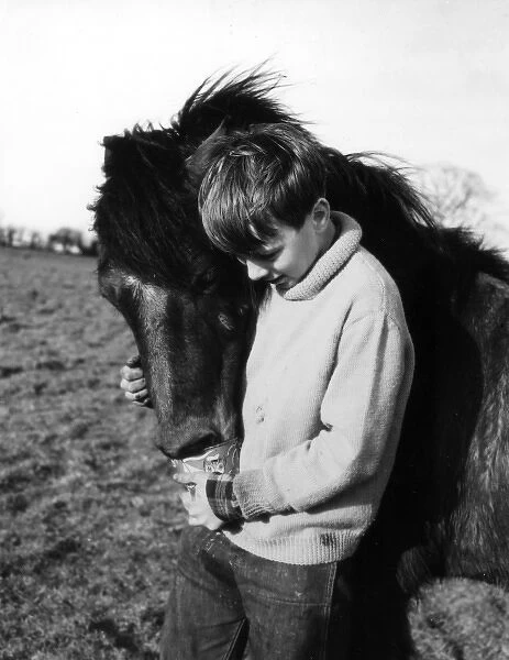 PONY BOY. Study of a boy giving his pony a loving cuddle. Date: 1960s