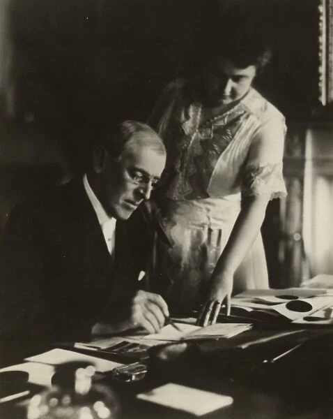 President Woodrow Wilson, seated at desk with his wife, Edit