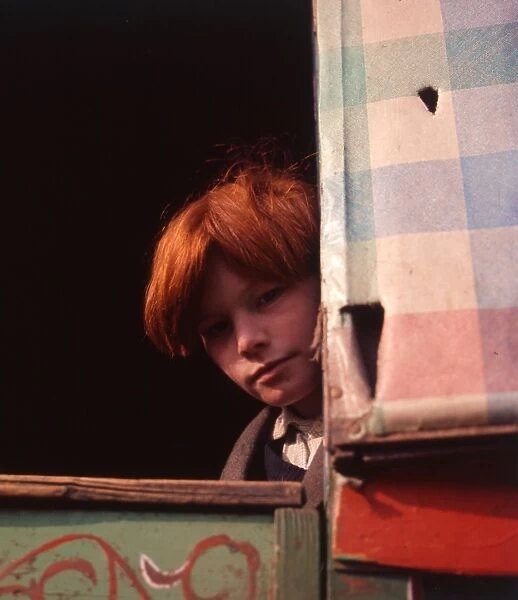 Red-haired gipsy boy looking out of his caravan