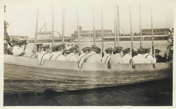 Ships crew in rowing boat with oars held vertically