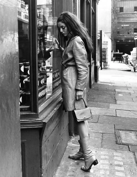 SHOPPING. A woman looks at a can of food through a shop window. Date: late 1960s