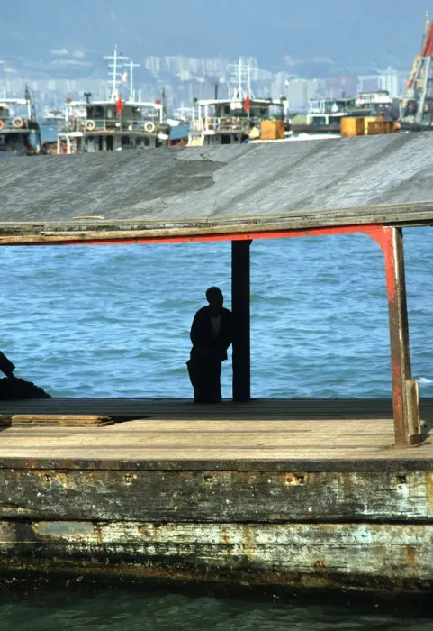 Framed Print : Silhouette of man sat on a bollard on a pier in Hong Kong Framed Print : Silhouette of man sat on a bollard on a pier in Hong Kong