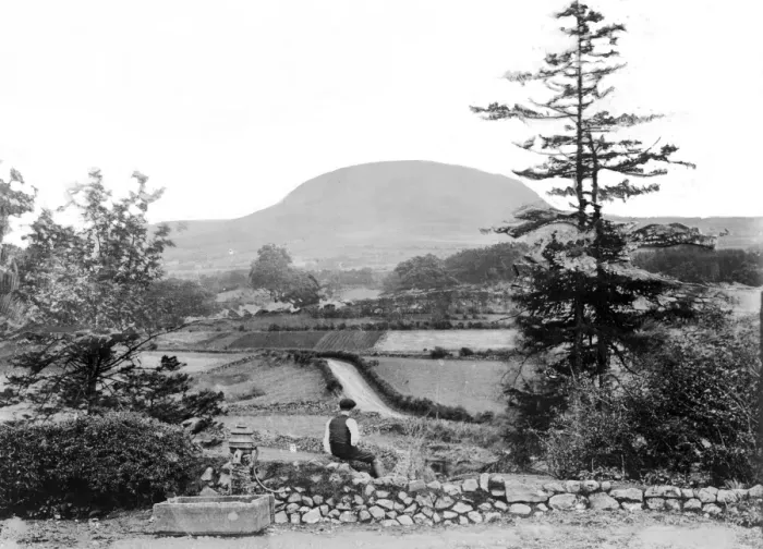 Framed Print : Slemish - a view of Slemish with a man in the foreground sitting beside a water pump Framed Print : Slemish - a view of Slemish with a man in the foreground sitting beside a water pump