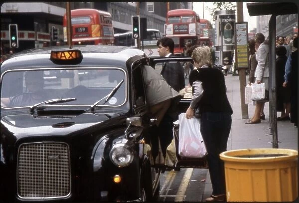 Two smartly dressed women pile into a London black taxi cab, after a spot of shopping on Oxford Street. Date: 1981