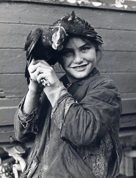 Smiling gipsy girl holding a chicken