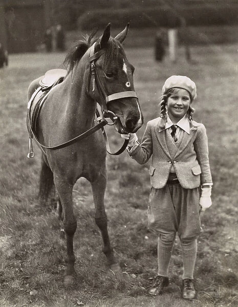 Smiling girl with her pony in a field