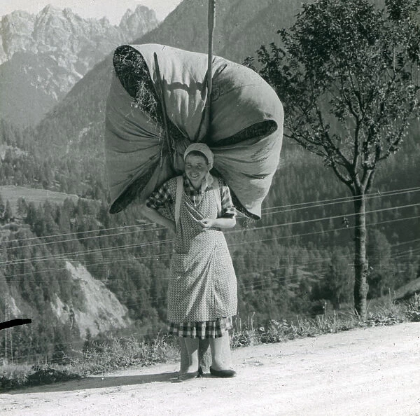 Spanish woman carrying a massive bundle of hay
