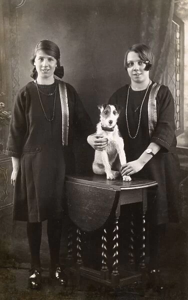 Studio portrait, two girls with terrier
