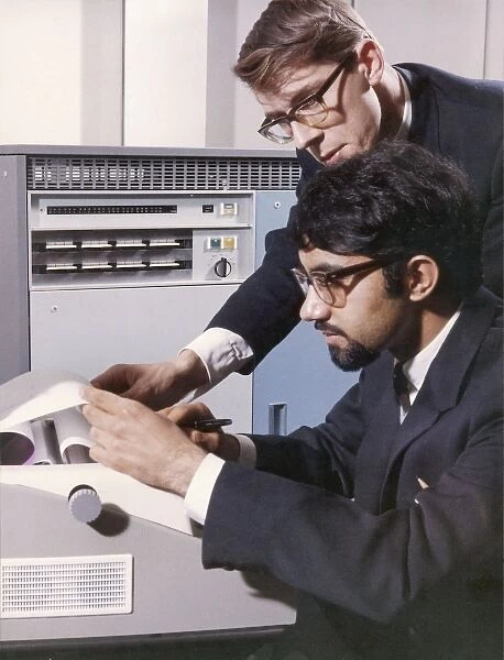Two technicians check a computer printout