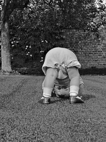 Toddler bending over in a garden