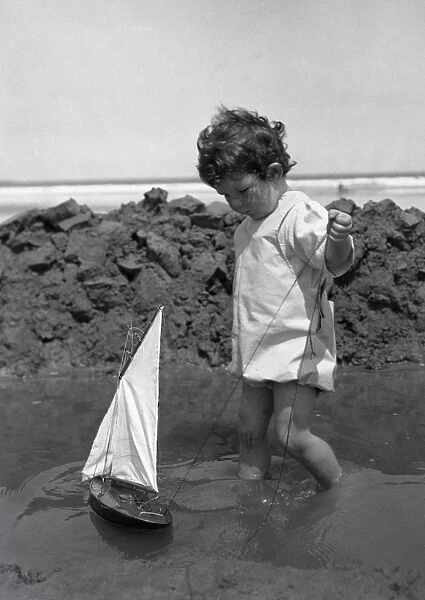 Toddler with sailing boat at seaside