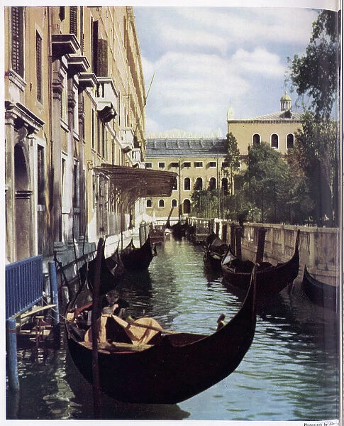 Tranquil scene of a gondola on a canal in Venice. Date: 1954