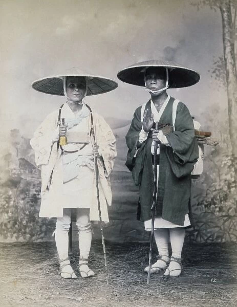 Two travelers with staffs, wearing hats, studio portrait