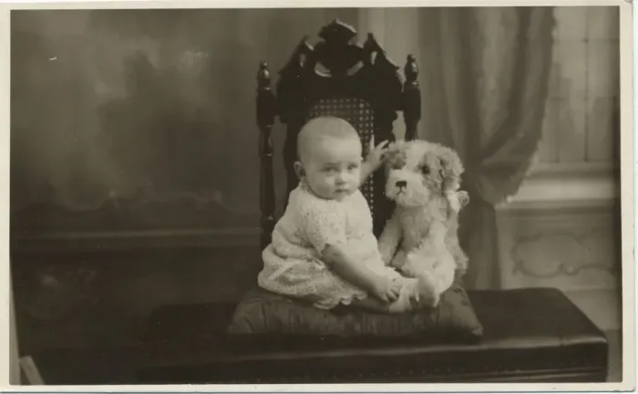 Framed Print : An unimpressed baby has his photograph taken with a cuddly toy dog. Date: c. 1950 Framed Print : An unimpressed baby has his photograph taken with a cuddly toy dog. Date: c. 1950