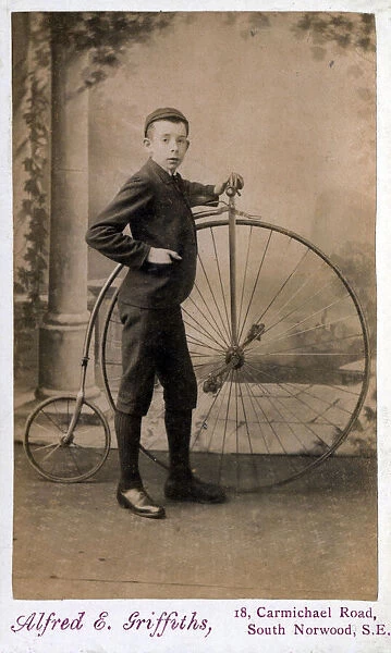 Victorian boy standing proudly alongside his Penny Farthing