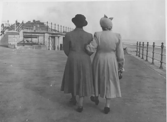 Framed Print : Back view of two ladies walking along an unidentified sea front arm in arm. Date: c Framed Print : Back view of two ladies walking along an unidentified sea front arm in arm. Date: c