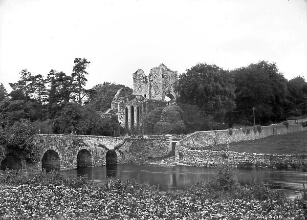 View of a stone arched bridge and ruined Abbey behind