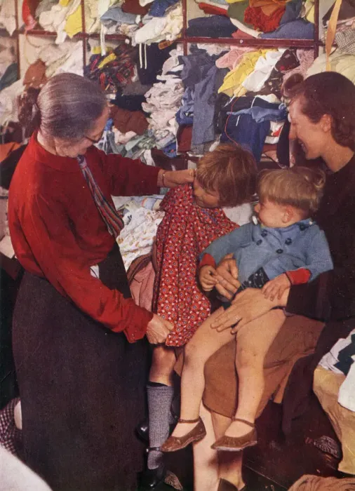 Framed Print : A W. V. S. worker selecting a frock for a little girl Framed Print : A W. V. S. worker selecting a frock for a little girl