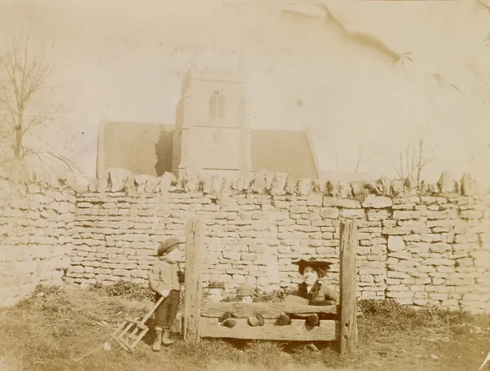 Framed Print : Woman and three boys in or by the stocks, possibly in Oxfordshire, with a church in the background. Date: circa 1890 Framed Print : Woman and three boys in or by the stocks, possibly in Oxfordshire, with a church in the background. Date: circa 1890