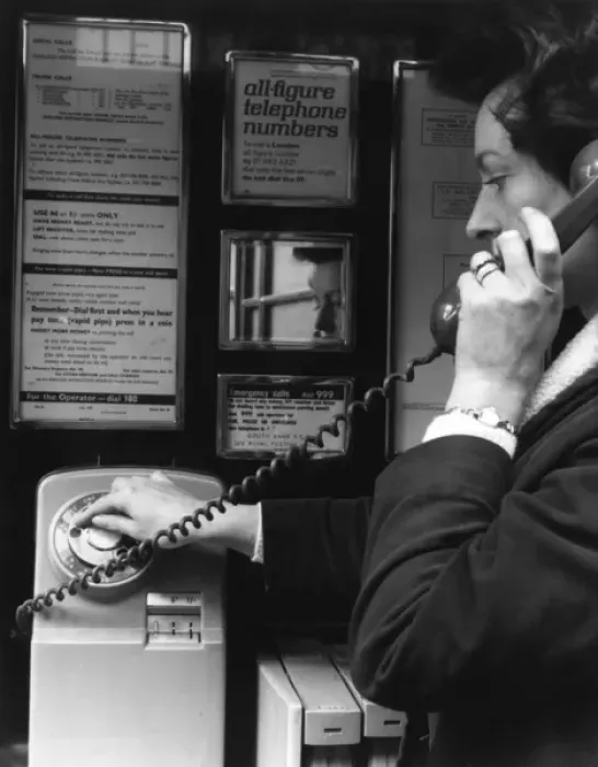 Framed Print : Woman dialling 999 in a public telephone box, London Framed Print : Woman dialling 999 in a public telephone box, London