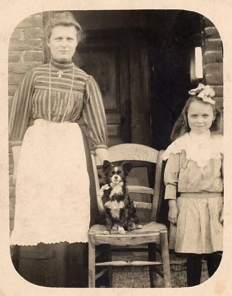 Woman and girl with dog outside a house, Belgium