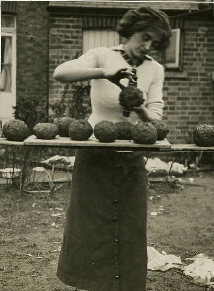 Woman making balls of clay and slack, West Country