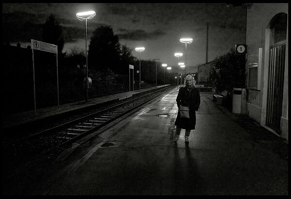 Woman on railway station platform late evening, Italy