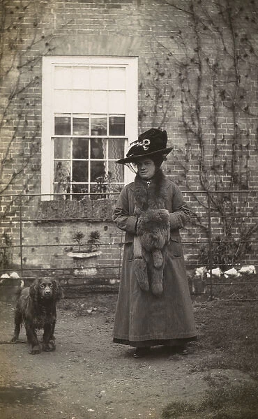 Woman with spaniel dog outside a house