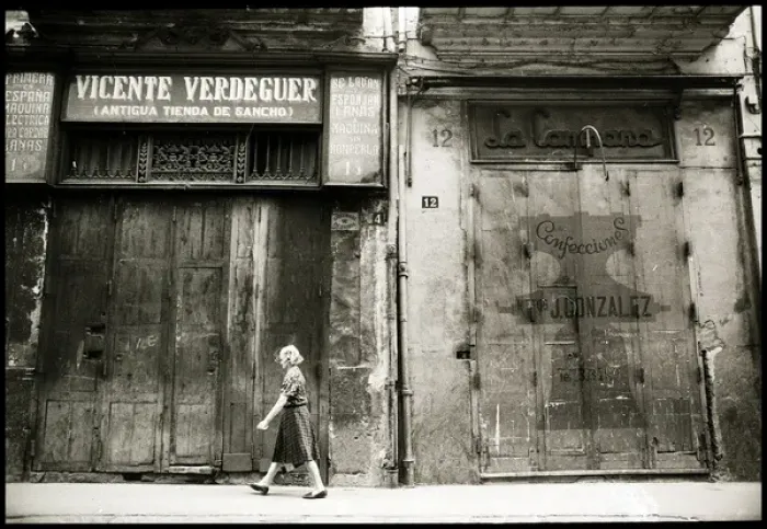 Framed Print : Woman walking in front of boarded up shops, Valencia, Spain Framed Print : Woman walking in front of boarded up shops, Valencia, Spain