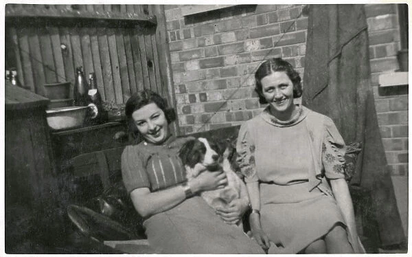 Two women with a dog in a back garden