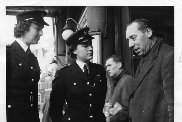 Two women police officers talking to man, London