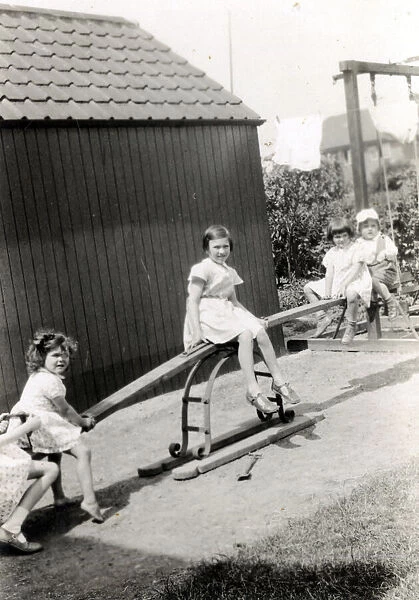 Four young children playing on a see-saw