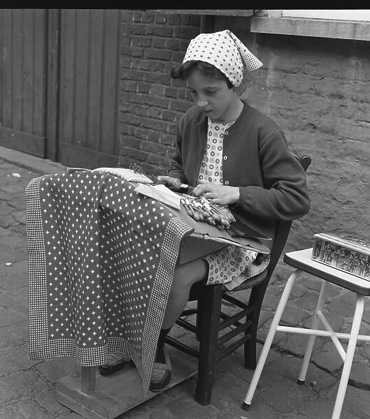 Young girl making lace on the pavement