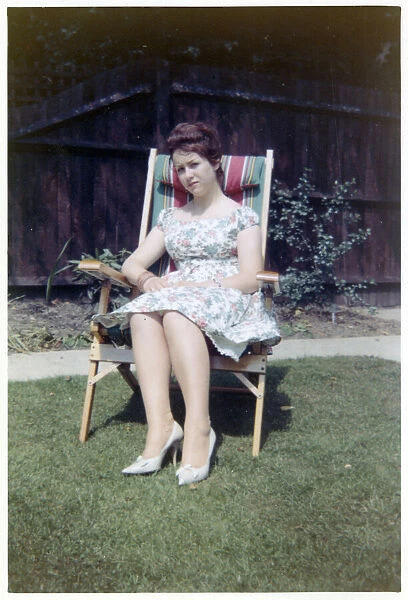 A young lady sat in a neat garden in a canvas-backed chair