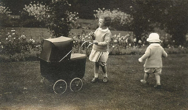 Two young siblings playing with a beautiful toy pram