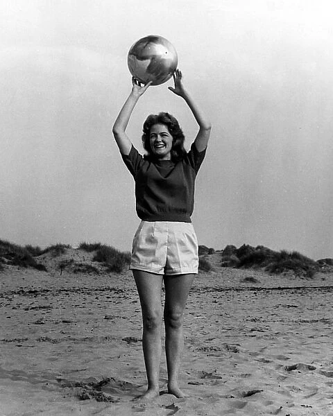 Young woman with ball on beach