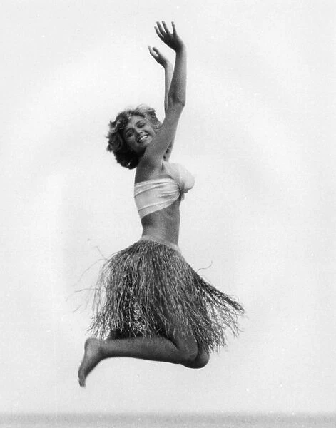 Young woman jumping in a grass skirt, West Country